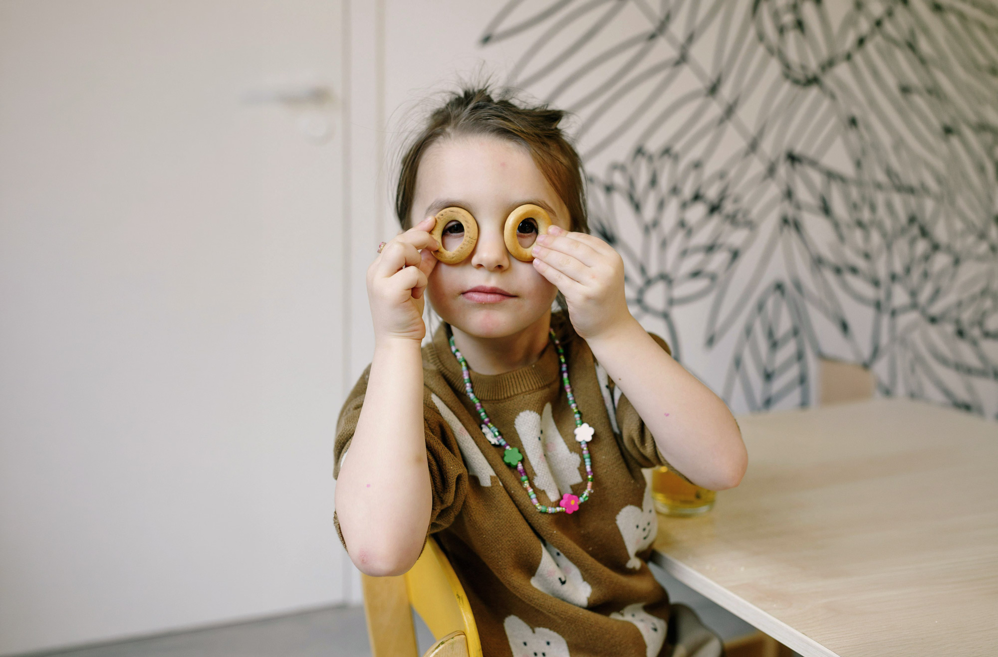 Ein Kind im Kindergarten Kraichgau-Hüpfer hält runde Kekse vor die Augen und schaut spielerisch durch die Öffnungen.